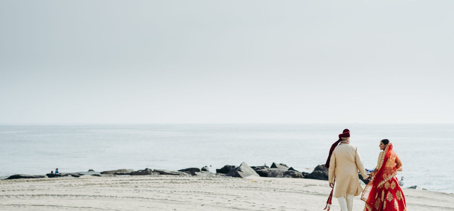 Hindu wedding couple walks along the ocean shore